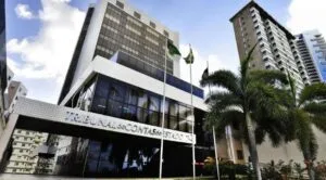Sede do Tribunal de Contas do Estado do Rio Grande do Norte (TCE-RN), em Natal, com fachada moderna e bandeiras, tema do curso Discursiva na Prática para a prova discursiva do concurso.