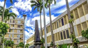 Edifícios com palmeiras e monumento, em imagem de divulgação do concurso ISS Caruaru para Auditor Fiscal Municipal.